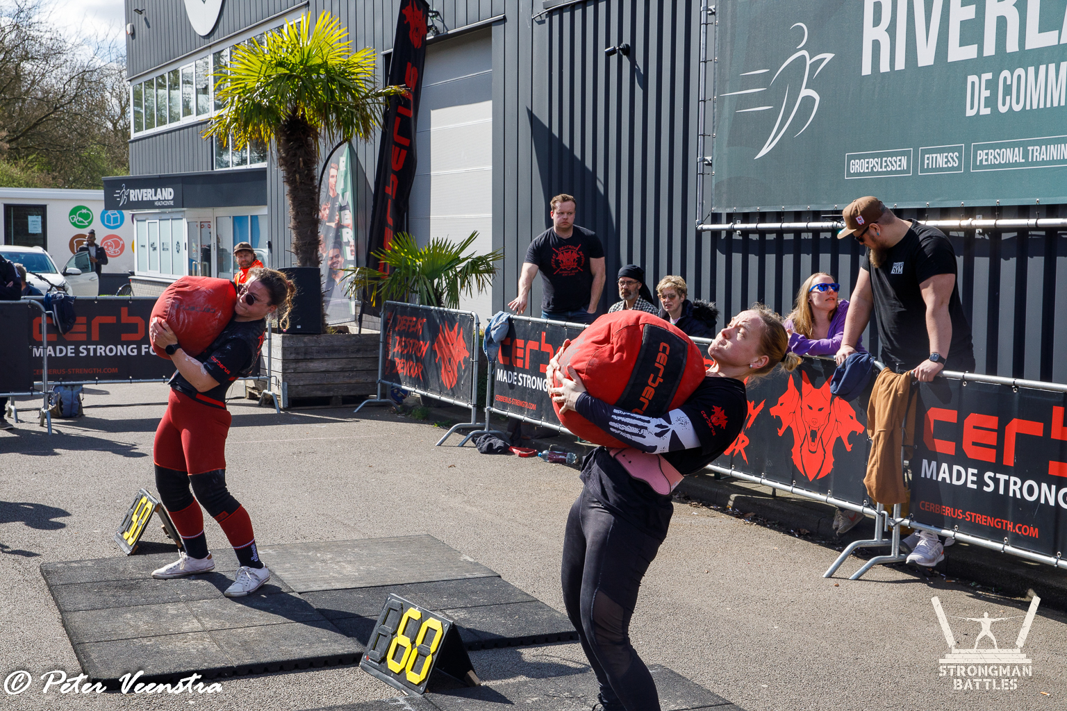 Two athletes lifting red sandbags at Natural Strongman in 2025