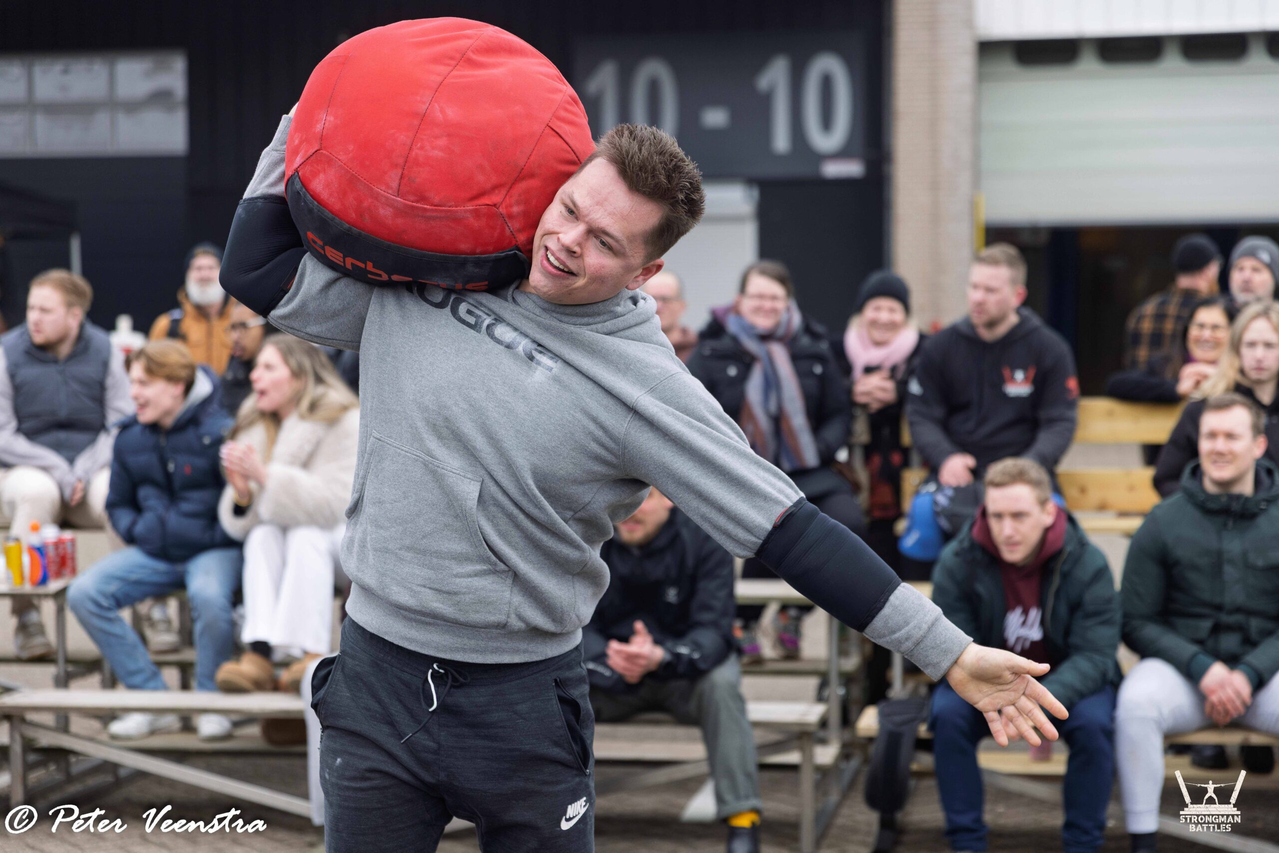 An athlete carrying a red sandbag at Strongman Battles Eindhoven